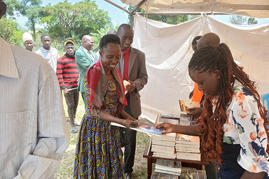 Ochorus sharing books, and Bibles to ministers during a conference in Tororo district.